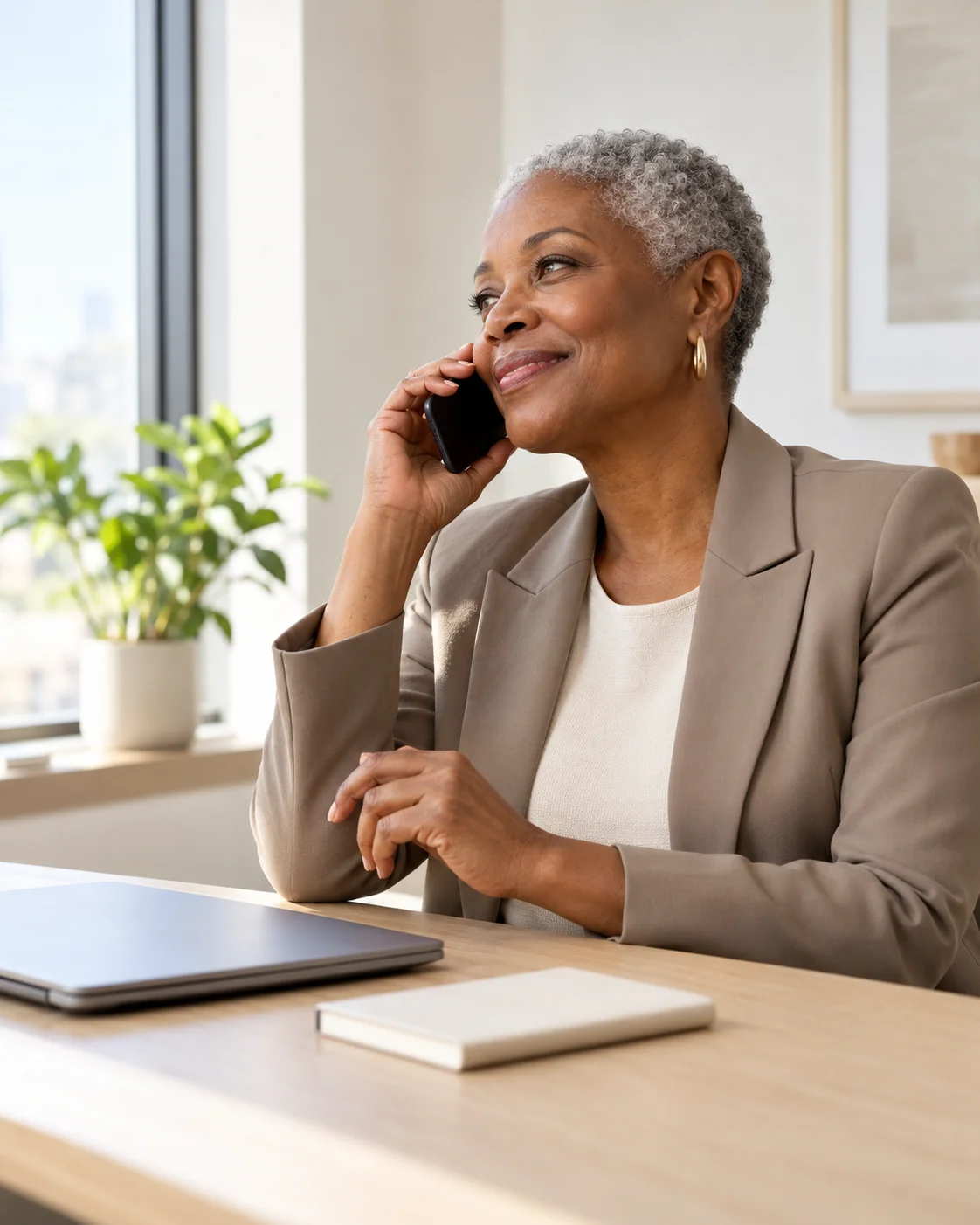 A community manager finishes a warm phone call in a calm office, with a closed laptop and notebook on the desk